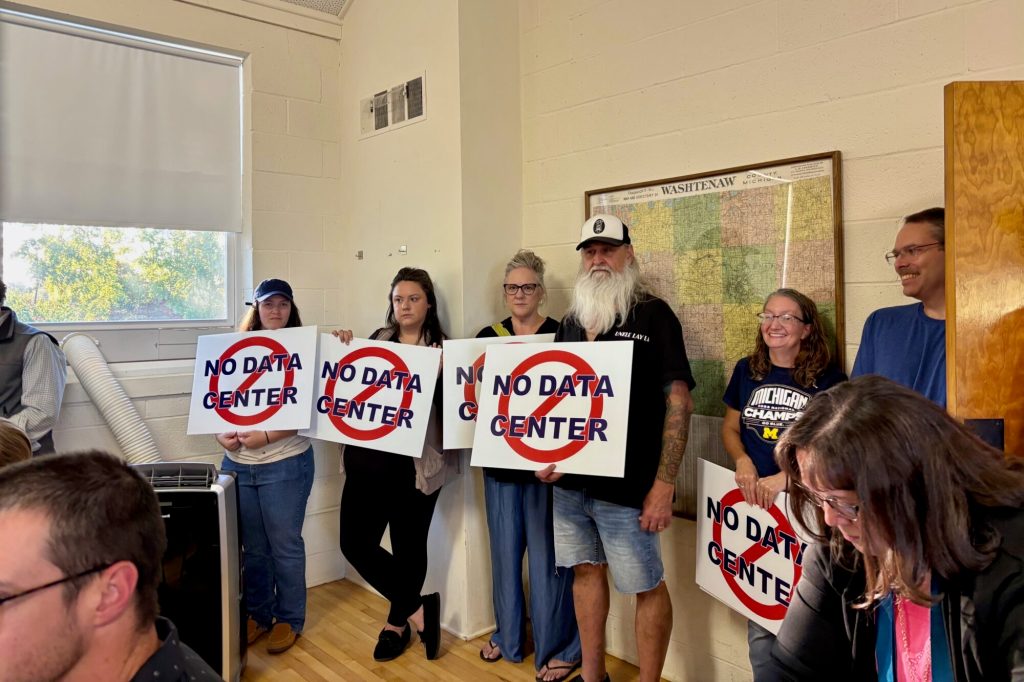Residents hold anti-AI signs in local meeting