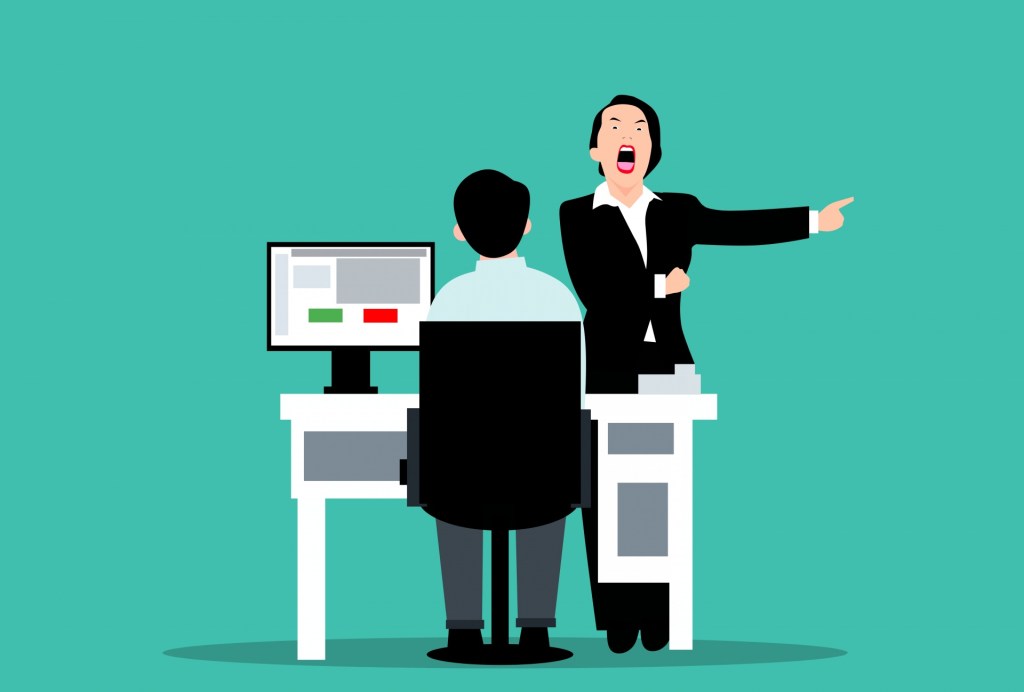 An angry boss yells at a seated worker